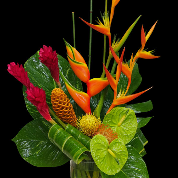 Tropical bouquet with orange bird-of-paradise and red ginger in a glass vase