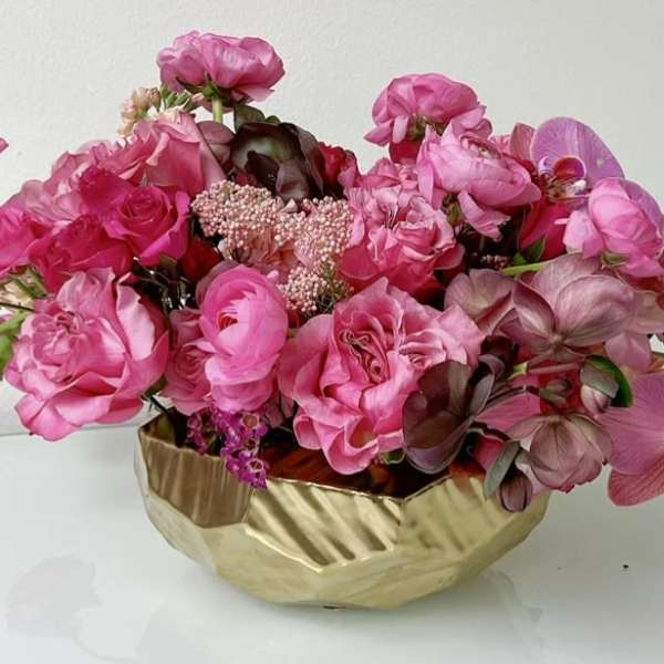 Pink floral arrangement in a gold bowl vase