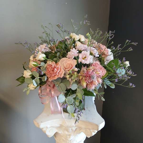 Pastel bouquet of roses, carnations, and small daisies with a pink ribbon