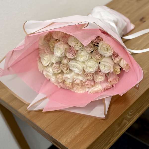 Bouquet of pale pink and white roses wrapped in pink paper