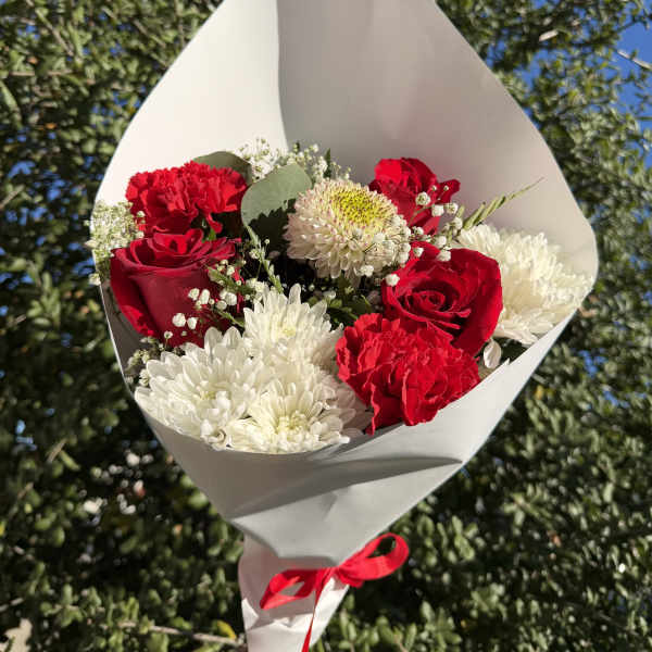 Bouquet of red roses, red carnations, and white chrysanthemums wrapped in white paper