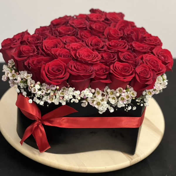 Red roses arranged in a black box with a red ribbon