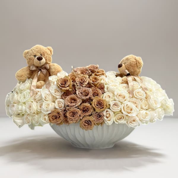 White and tan rose arrangement in a white bowl with two teddy bears