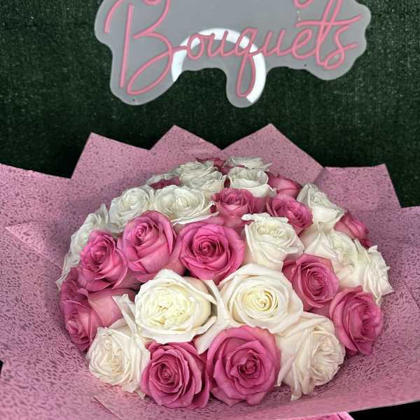 Bouquet of pink and white roses wrapped in pink paper
