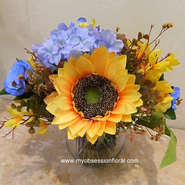 Sunflower bouquet with blue and yellow flowers in a glass vase