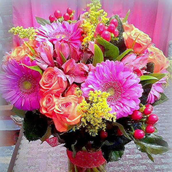 Bouquet of pink gerbera daisies and peach roses in a clear vase