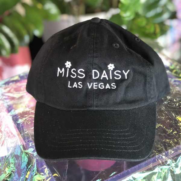 Black baseball cap with white "Miss Daisy Las Vegas" embroidery