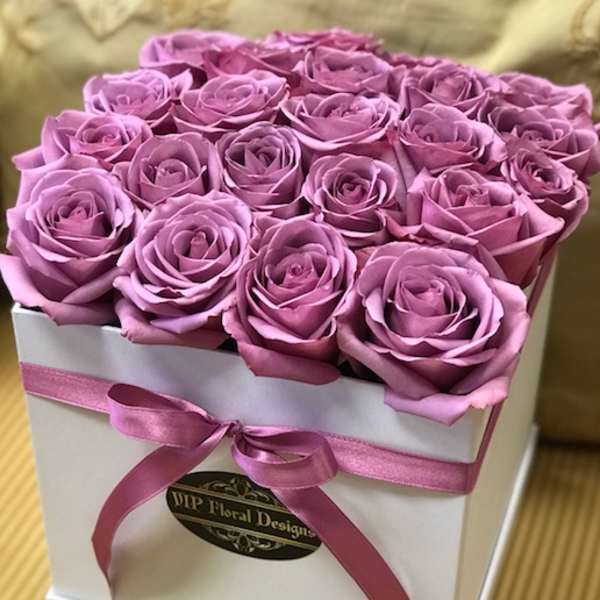 Pink roses arranged in a white square box with a ribbon bow