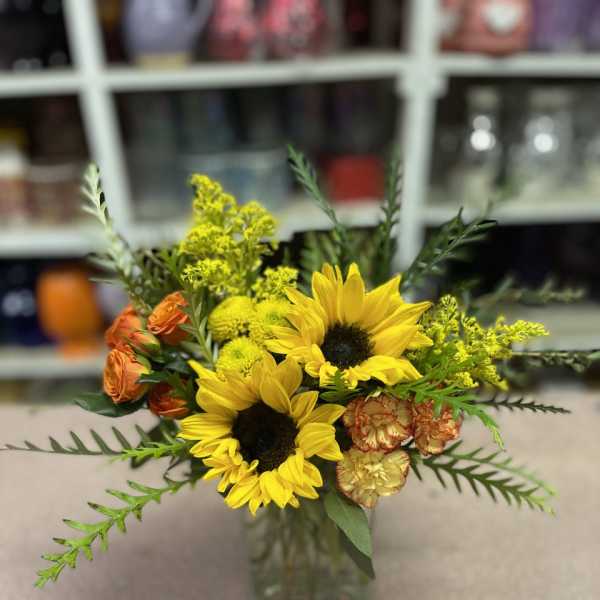 Sunflower bouquet with orange roses in a glass vase