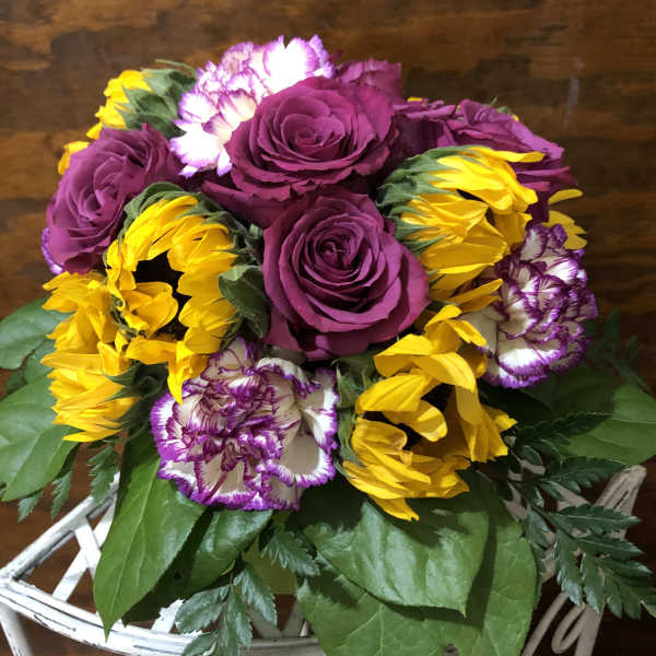 Bouquet of purple roses, yellow sunflowers, and white-purple carnations