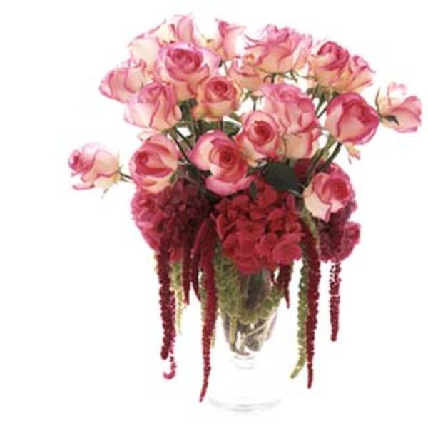 Pink roses and red hanging flowers in a clear vase