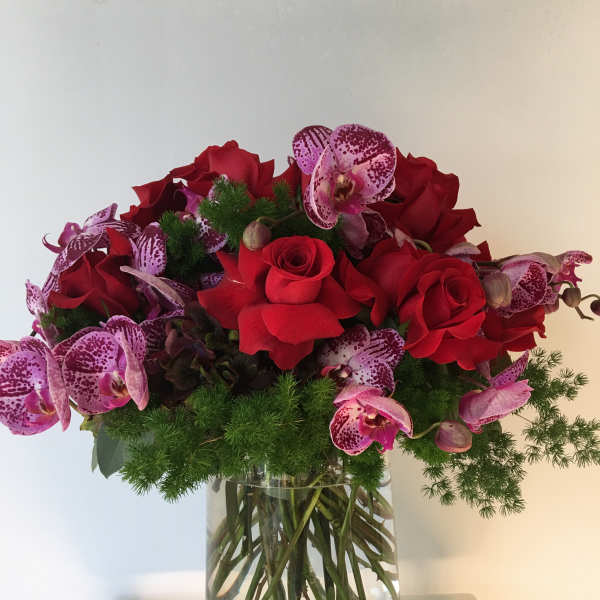 Red roses and pink orchids arranged in a glass vase