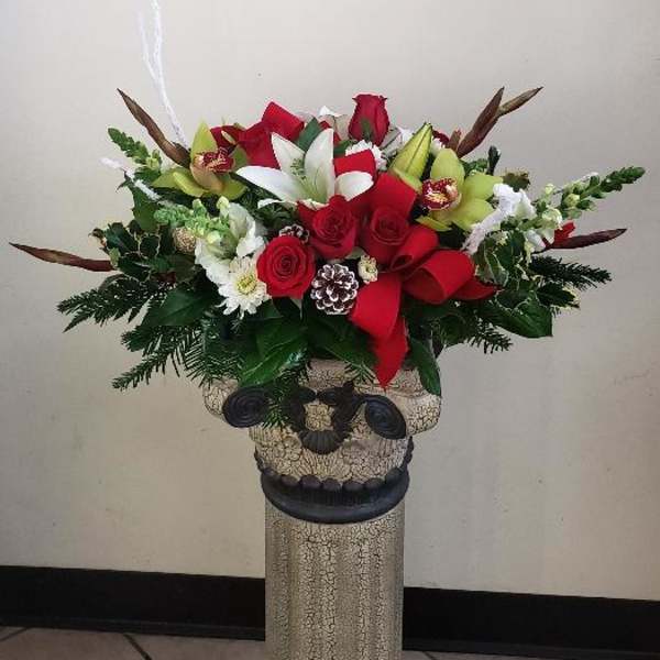 Red and white floral arrangement in a decorative pedestal vase