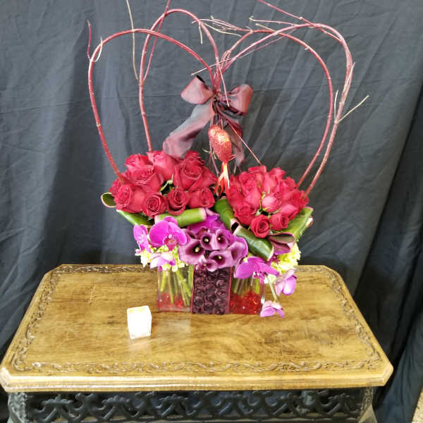 Heart-shaped rose arrangement with purple orchids in a vase