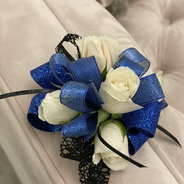 White rose corsage with blue ribbon and black accents