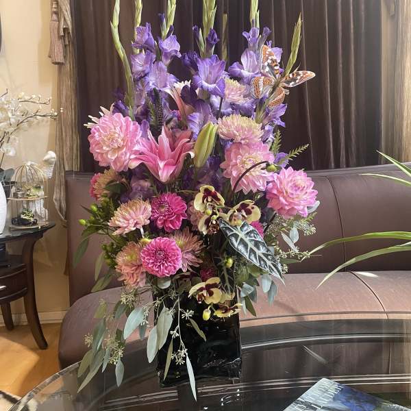 Tall bouquet of pink and purple flowers in a black vase