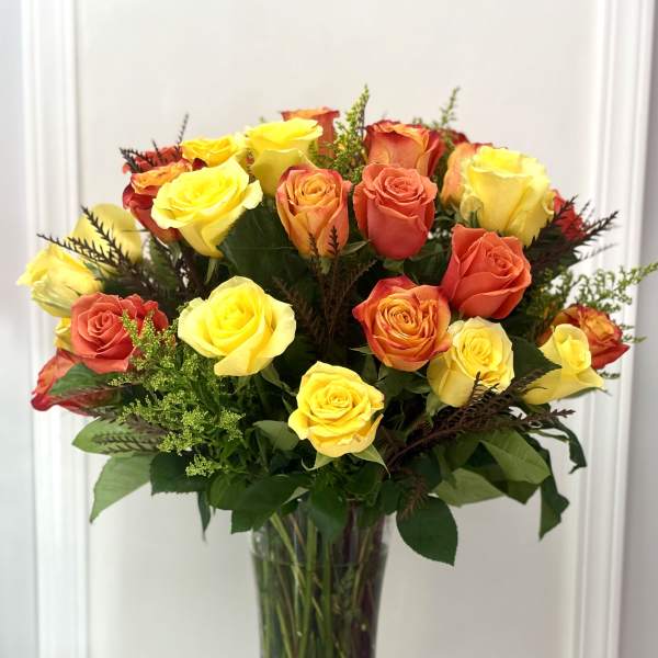 Bouquet of yellow and orange roses in a clear glass vase