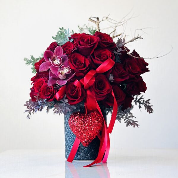 Red rose bouquet with orchids in a blue vase and heart decoration