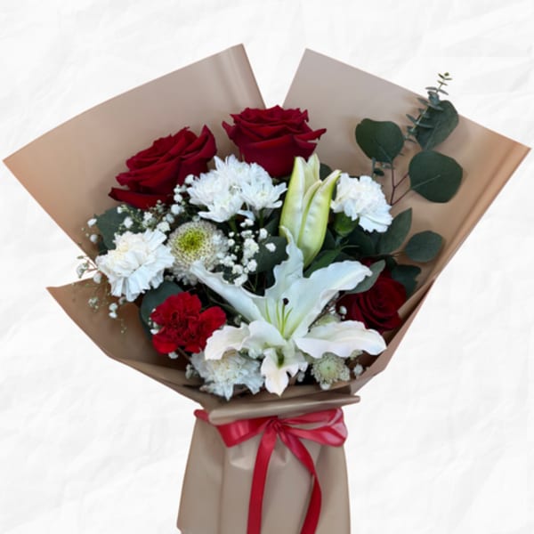 Bouquet of red roses, white lilies, and white carnations wrapped in brown paper