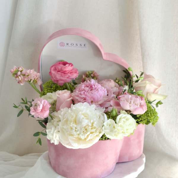 Pink and white flowers arranged in a heart-shaped pink box