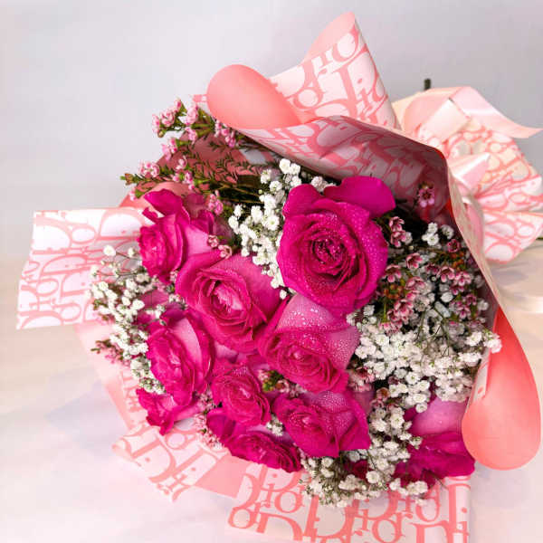 Bouquet of hot pink roses with white filler flowers in pink wrapping
