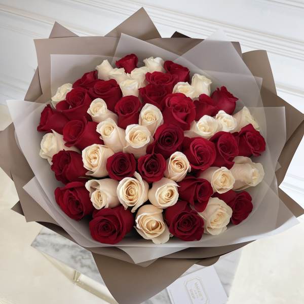 Bouquet of red and cream roses wrapped in brown and translucent paper