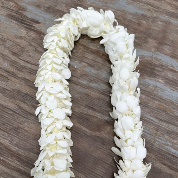 White flower lei laid in a U shape on a wooden surface