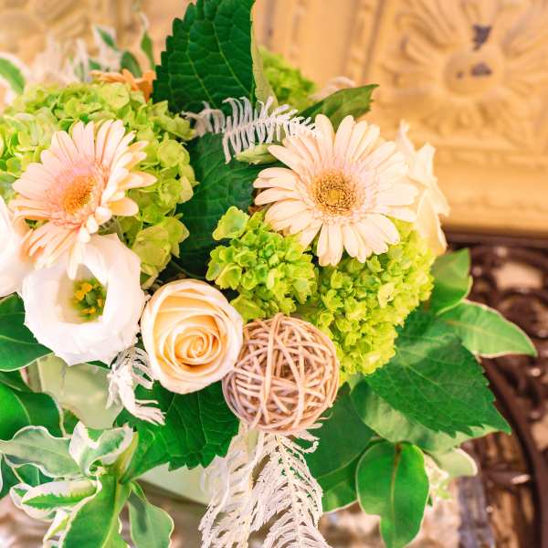 Bouquet of pale peach flowers and green hydrangeas with decorative accents