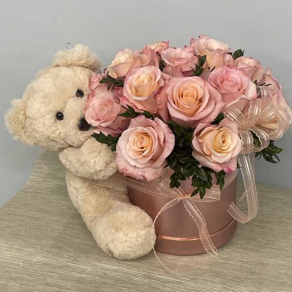 Pink rose arrangement in a round box with a teddy bear