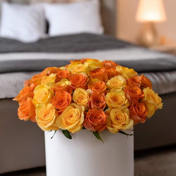 Orange and yellow roses arranged in a white hat box