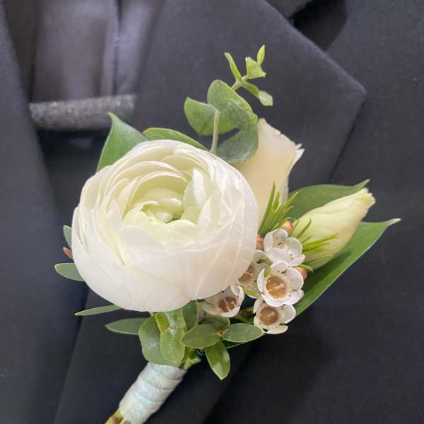 White boutonniere with a ranunculus bloom and small white flowers