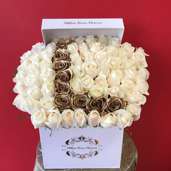 Boxed arrangement of cream and gold roses against a red background