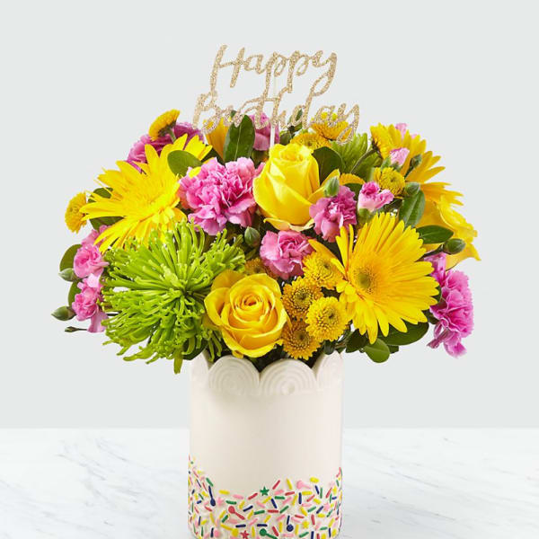 Bright mixed bouquet in a white vase with a glittery "Happy Birthday" topper