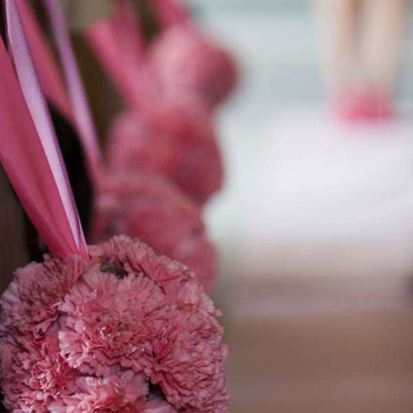 Pink carnation pomander with ribbon hanging indoors