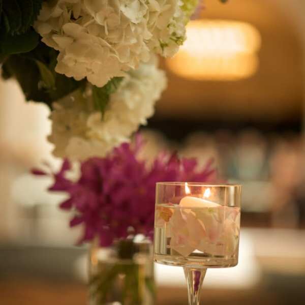 White hydrangea arrangement beside a floating candle in a glass holder