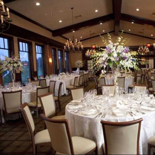 Round banquet tables with tall floral centerpieces in a formal dining room