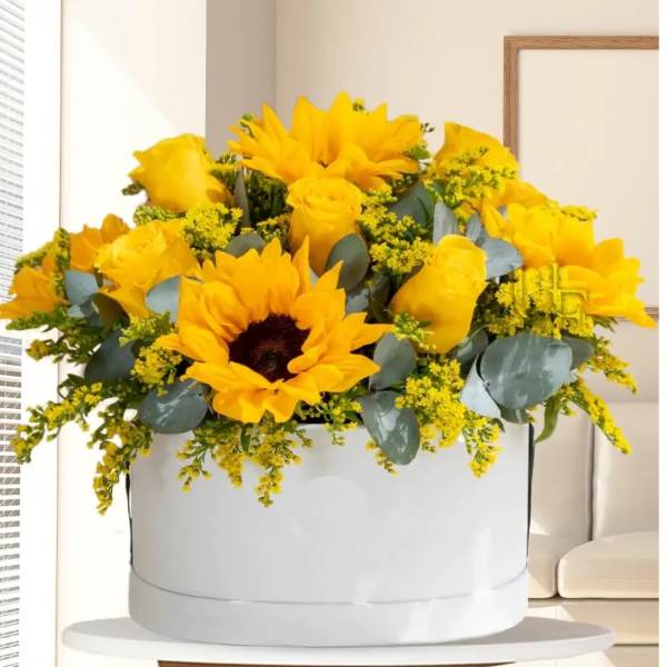 Yellow roses and sunflowers arranged in a white hat box
