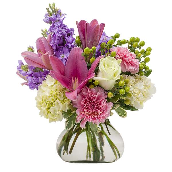 Pink lilies, purple stock, white roses, and carnations in a glass vase