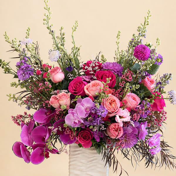 Pink and purple mixed flower arrangement in a white vase