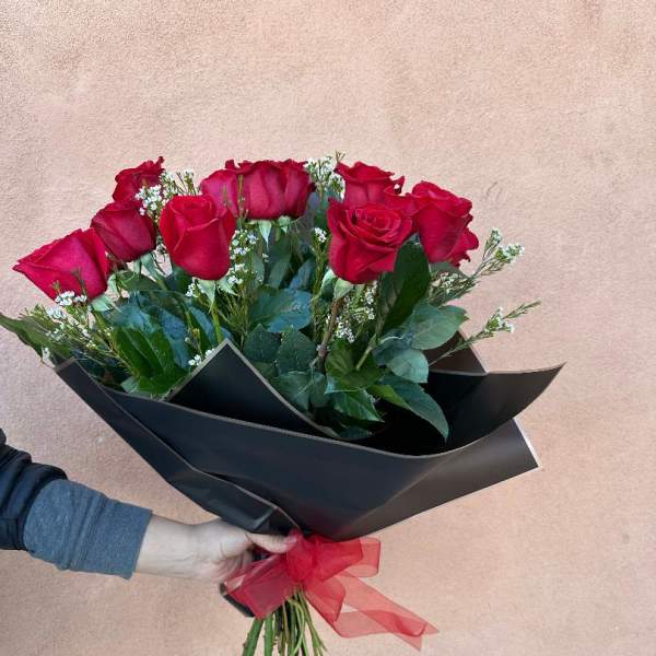 Bouquet of red roses wrapped in black paper with a red ribbon