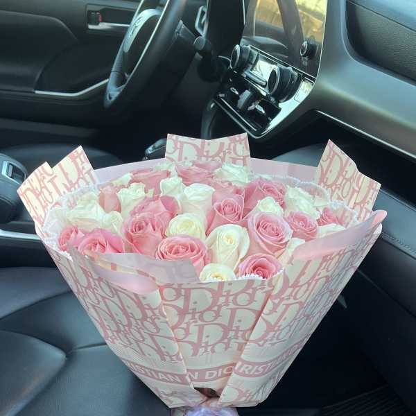 Pink and white rose bouquet wrapped in patterned paper with a ribbon