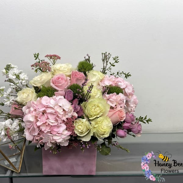 Pink and cream rose arrangement with hydrangeas in a pink box