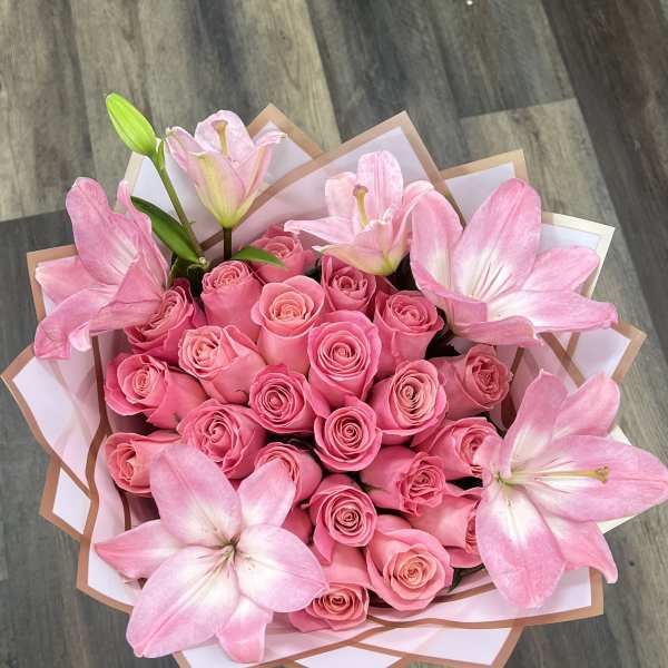 Pink rose bouquet with large pink lilies wrapped in white and tan paper