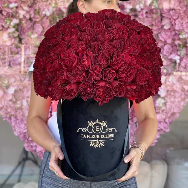 Large bouquet of deep red roses in a black hatbox