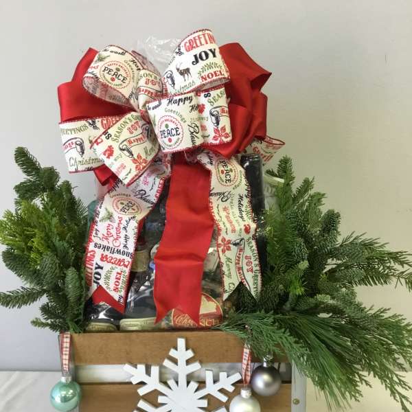 Christmas gift basket with a large red bow, evergreen branches, and a snowflake ornament