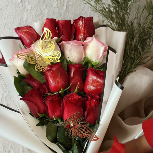 Bouquet of red and pale pink roses wrapped in white paper with a red ribbon