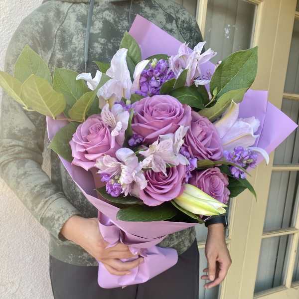 Bouquet of pink roses and lilies wrapped in lavender paper