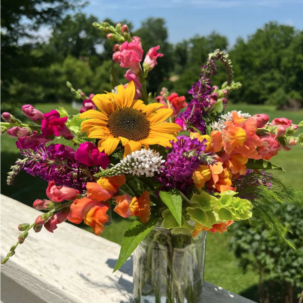 Colorful bouquet with a sunflower and snapdragons in a glass vase