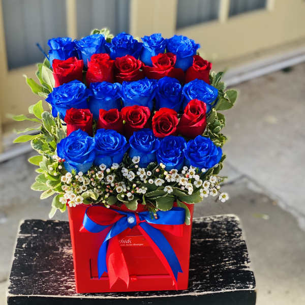 Red and blue roses arranged in a red box with a ribbon