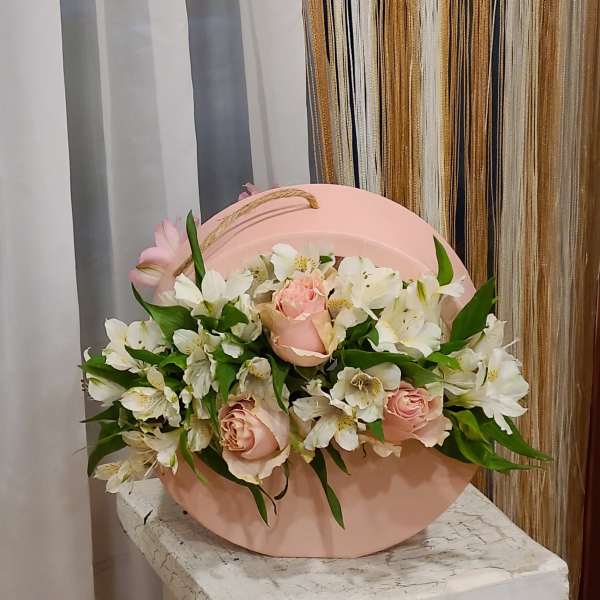 Pink roses and white lilies arranged in a round pink box